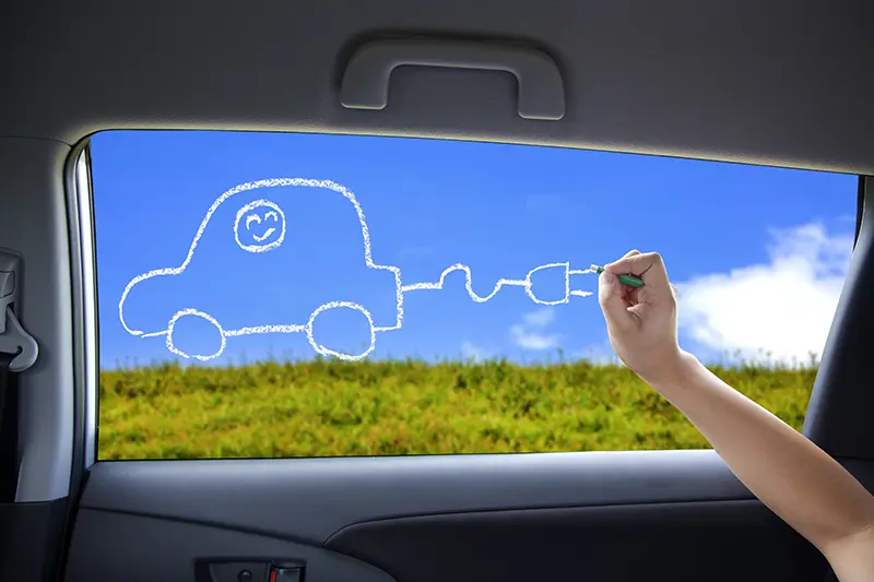 child drawing electric car on car window
